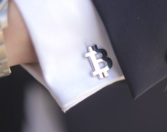 Puede incluir: Gemelos de plata con forma de símbolo de Bitcoin, una "B" estilizada.
