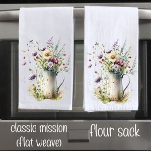 May include: Two white kitchen towels with a watercolour floral design. The design features a bouquet of wildflowers in a vintage pitcher. The towels are labelled "classic mission (flat weave)" and "flour sack".