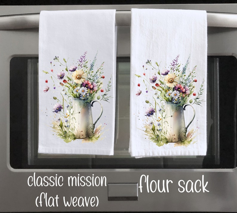 May include: Two white kitchen towels with a watercolour floral design. The design features a bouquet of wildflowers in a vintage pitcher. The towels are labelled "classic mission (flat weave)" and "flour sack".