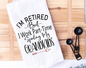 May include: White kitchen towel with black text that reads "I'm Retired - But I Work Part-Time Spoiling My Grandkids" with a red arrow and heart.