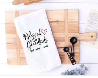 May include: White kitchen towel with the text "Blessed with Grandkids" and a red heart. The names Sam, Mary, and Jane are listed below the text.