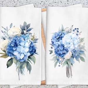 Può includere: Due asciugamani da cucina bianchi con motivi floreali di ortensie blu. Le ortensie sono in stile acquerello e hanno una gamma di colori blu chiaro e blu scuro.