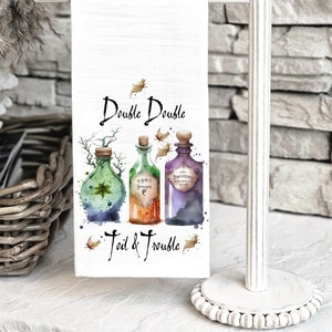 May include: White kitchen towel with a watercolor illustration of three potion bottles and the text "Double Double Toil & Trouble".