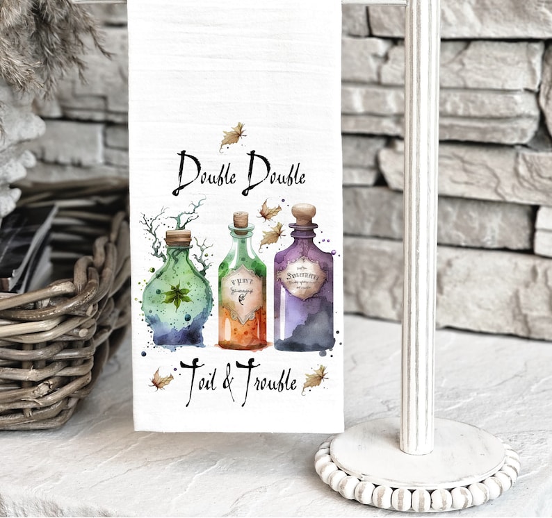 May include: White kitchen towel with a watercolor illustration of three potion bottles and the text "Double Double Toil & Trouble".