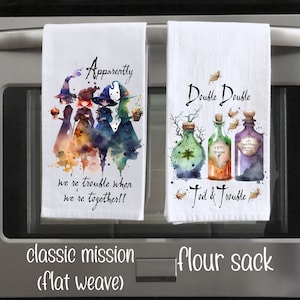 May include: Two kitchen towels with a Halloween theme. The first towel features a watercolor illustration of three witches with the text "Apparently we're trouble when we're together!!". The second towel features a watercolor illustration of three potion bottles with the text "Double Double Foil & Trouble".