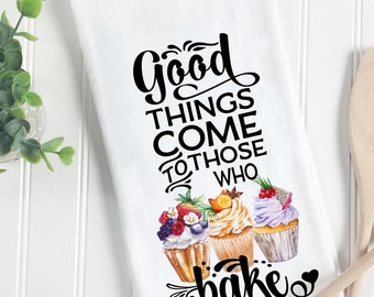Può includere: Un asciugamano da cucina bianco con il testo "Good things come to those who bake" in corsivo nero. Tre cupcake ad acquerello con diverse guarnizioni sono sotto il testo.