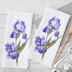 Puede incluir: Dos toallas de cocina blancas con una ilustración de acuarela de flores de iris moradas. Las flores están pintadas en tonos de morado, azul y verde.