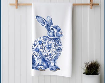 May include: A white kitchen towel featuring a blue and white rabbit design. The rabbit is depicted in a traditional blue and white porcelain style with floral patterns.