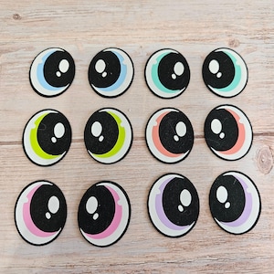 May include: Twelve colourful googly eyes with black pupils and white highlights. The eyes are arranged in three rows of four. The eyes are on a light brown wooden surface.