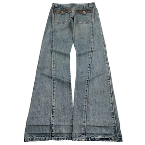 May include: Light blue denim jeans with a flared leg design. The jeans feature decorative stitching down the front and back, with two back pockets. The pockets have a brown decorative trim. The jeans are laid flat on a white surface.