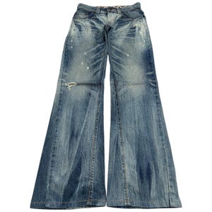 May include: Light blue denim jeans with a wide leg. The jeans have a distressed appearance with faded areas and small rips. The waistline features a patterned fabric detail. A classic, casual style.