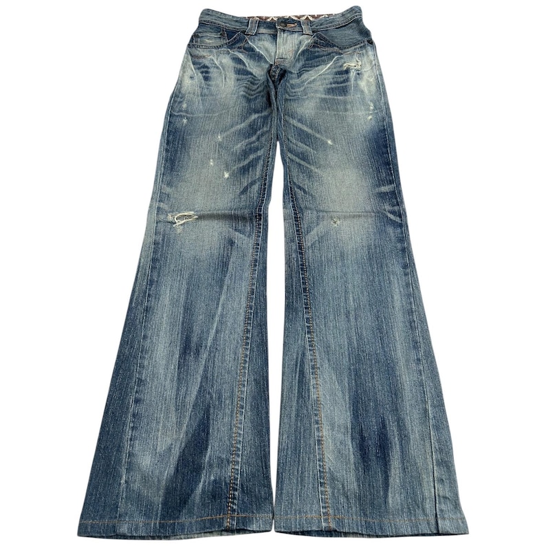 May include: Light blue denim jeans with a wide leg. The jeans have a distressed appearance with faded areas and small rips. The waistline features a patterned fabric detail. A classic, casual style.
