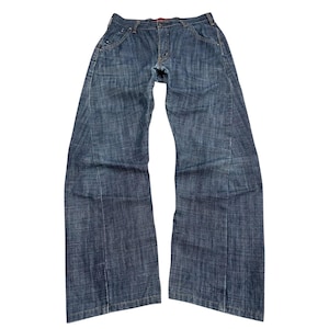 May include: Blue denim jeans with a classic five-pocket design. The jeans have a button and zip closure, belt loops, and a red interior waistband. The legs are wide and straight, and the denim has a slightly faded appearance.