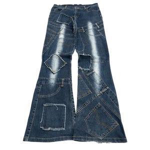 Puede incluir: Pantalones vaqueros de mezclilla azul oscuro con un diseño de parches que incluye múltiples paneles de tela cosidos, bordes deshilachados y reflejos blancos verticales desvanecidos. El pantalón tiene una silueta acampanada con costuras visibles.