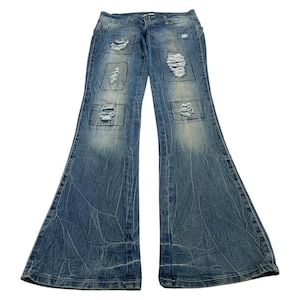 May include: Light blue denim jeans with a flared leg design. The jeans feature distressed patches in a square pattern across the front. The denim has a faded, worn appearance.