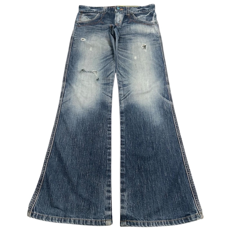 May include: Faded blue denim jeans with a wide, flared leg design. The jeans have a distressed look with intentional rips and fading. Classic five-pocket style with a button and zipper closure. The jeans are laid flat against a white background.