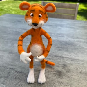 Puede incluir: Un juguete de peluche de tigre con rayas naranjas y negras, patas blancas y vientre blanco. El juguete tiene una cola larga y orejas grandes.