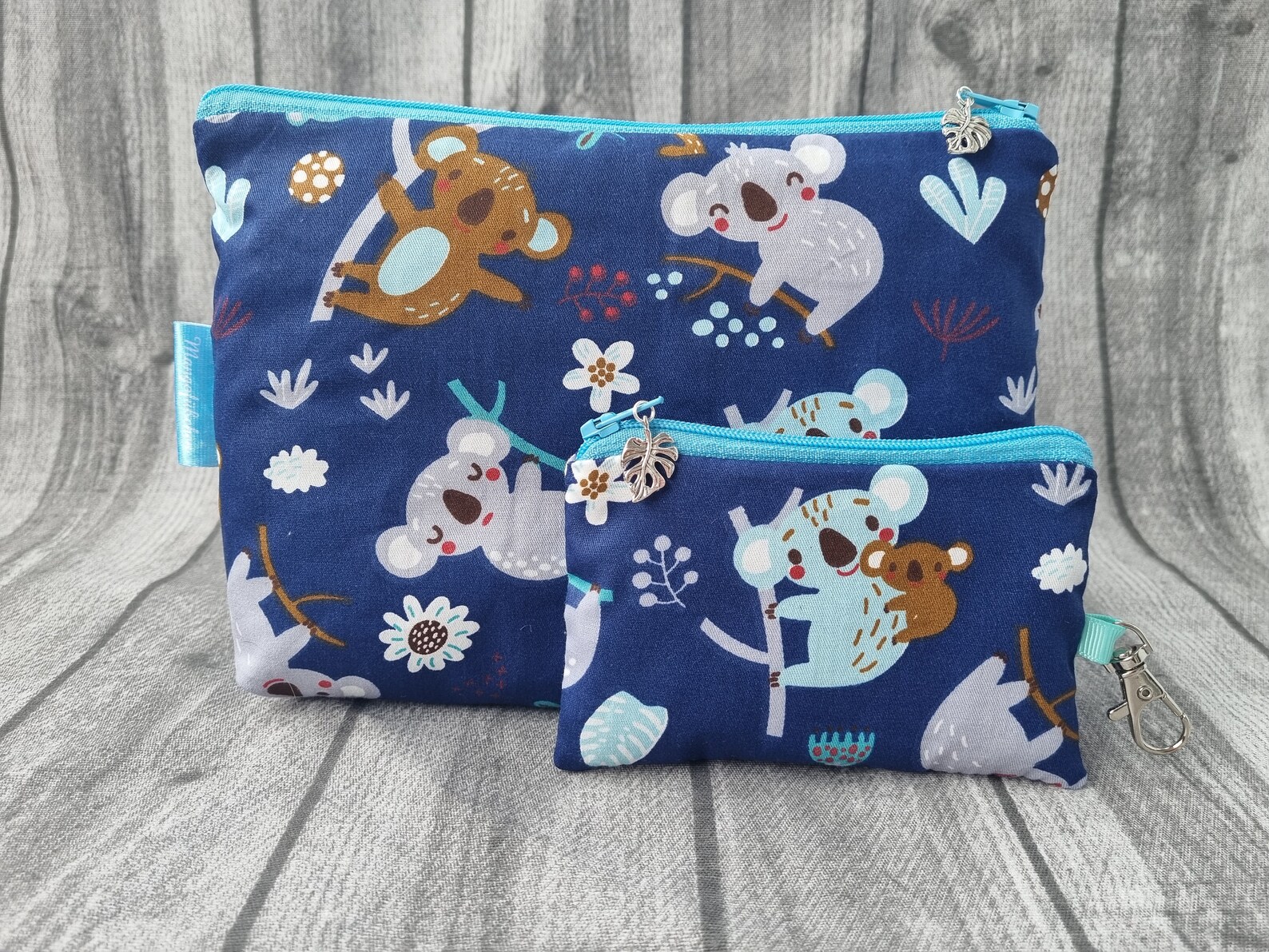 two blue cosmetic bags with koala prints on the side.