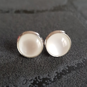 Op de afbeelding: Een paar zilveren oorbelletjes met witte, opalen-achtige stenen.