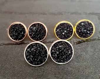 Pode incluir: Quatro pares de brincos de pressão de glitter preto com engastes de diferentes cores. Os brincos são redondos e estão engastados em prata, ouro e ouro rosa.