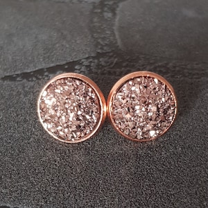 Könnte beinhalten: Ein Paar Ohrstecker aus Roségold mit einem funkelnden, glitzernden Finish.