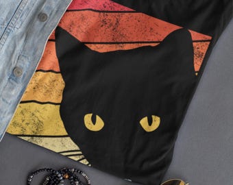 May include: Black t-shirt with a retro-style sunset graphic and a black cat silhouette. The cat's eyes are yellow.