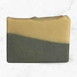 May include: A bar of soap with a light brown top layer and a dark green bottom layer.