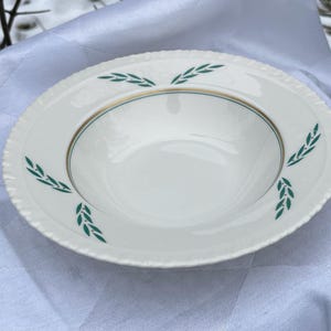 May include: White ceramic soup bowl with a green and gold rim and a green leaf design.
