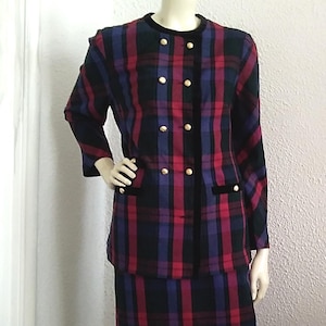 May include: A plaid skirt suit with a black velvet trim and gold buttons. The jacket has a double-breasted closure and the skirt is knee-length.