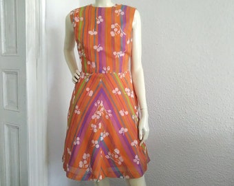 May include: A sleeveless orange dress with a multi-colored striped pattern and white floral print.
