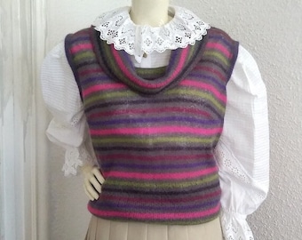 Puede incluir: Un chaleco de punto a rayas con cuello de pico. El chaleco es en tonos de rosa, morado, verde y gris. El chaleco se lleva sobre una blusa blanca con cuello de encaje.