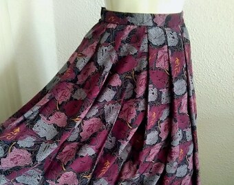 May include: A burgundy skirt with a pleated design and a floral print featuring grey, pink, and yellow leaves.