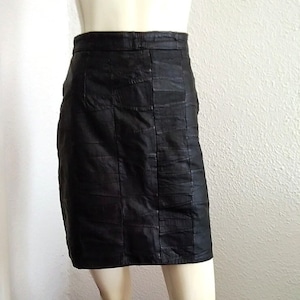 Può includere: Una gonna di pelle nera con un taglio dritto e una superficie leggermente strutturata.