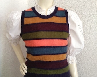 Puede incluir: Un chaleco de punto sin mangas a rayas en tonos azul marino, marrón, verde, naranja y verde azulado. El chaleco está tejido y tiene cuello redondo.