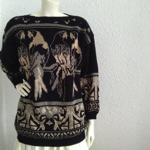 May include: Black knitted jumper with a gold and brown bird design. The jumper has a crew neck and long sleeves.