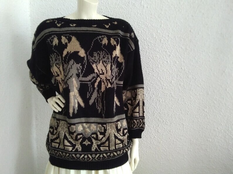 May include: Black knitted jumper with a gold and brown bird design. The jumper has a crew neck and long sleeves.