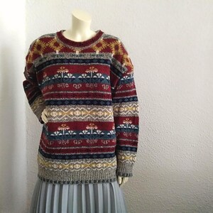 May include: A colorful striped sweater with a geometric pattern in shades of red, blue, yellow, and white.
