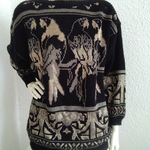 May include: Black and beige knitted sweater with a geometric pattern and bird design.