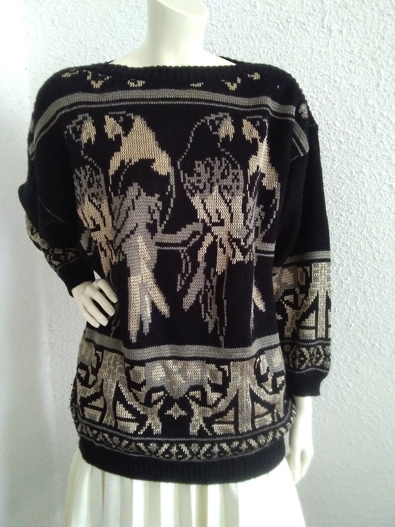 May include: Black and beige knitted sweater with a geometric pattern and bird design.