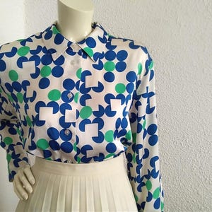 May include: A white long-sleeved button-up shirt with a geometric pattern of blue and green circles and squares.