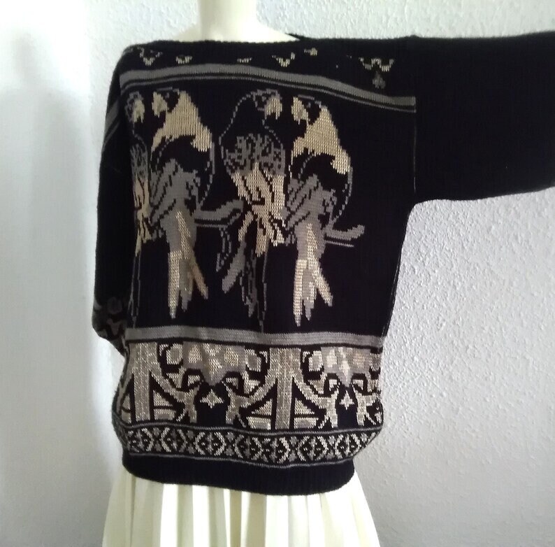 May include: Black knitted jumper with a beige and brown bird design. The jumper has a crew neck and long sleeves.