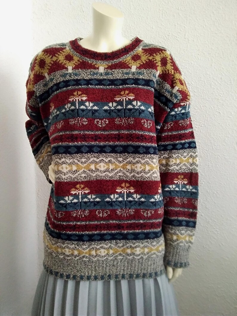 May include: A multi-colored striped sweater with a geometric pattern. The sweater is made of a soft, fuzzy material and has a crew neck.