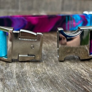 May include: A blue and purple patterned dog collar with a silver buckle and a silver D-ring.
