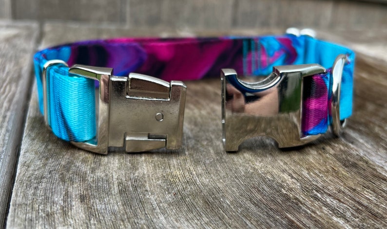 May include: A blue and purple patterned dog collar with a silver buckle and a silver D-ring.