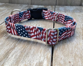 May include: A red, white and blue dog collar with a repeating pattern of American flags. The collar has a silver buckle and a silver D-ring.