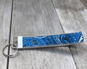 May include: A blue and white paisley patterned key chain with a silver key ring.