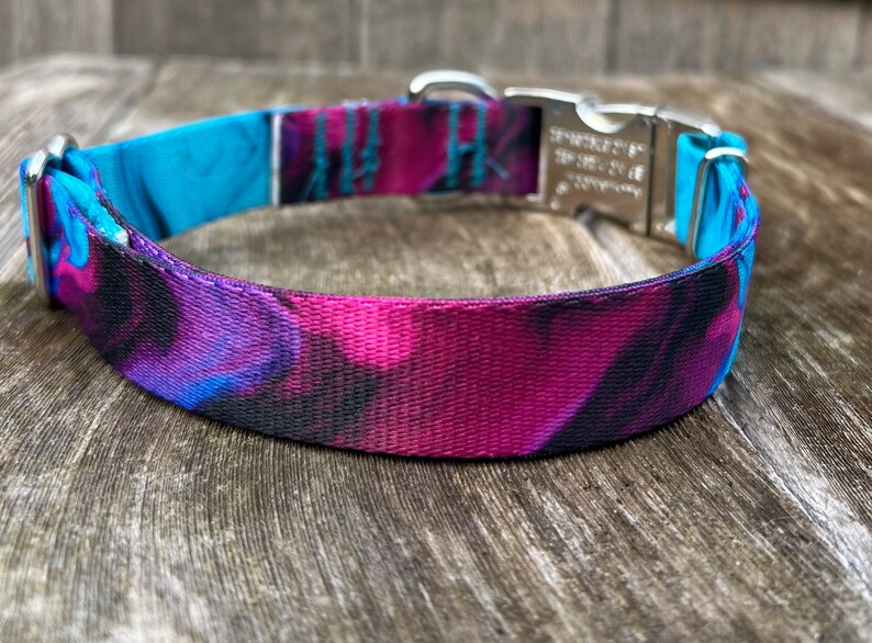 May include: A purple, blue, and black patterned dog collar with a silver buckle.