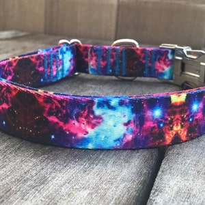 Puede incluir: Un collar para perro morado, azul y rosa con estampado de galaxia. El collar tiene una hebilla y un anillo en D plateados.