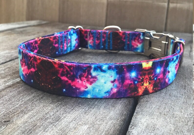 Puede incluir: Un collar para perro morado, azul y rosa con estampado de galaxia. El collar tiene una hebilla y un anillo en D plateados.