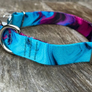 May include: A blue and purple patterned dog collar with a silver buckle and D-ring.